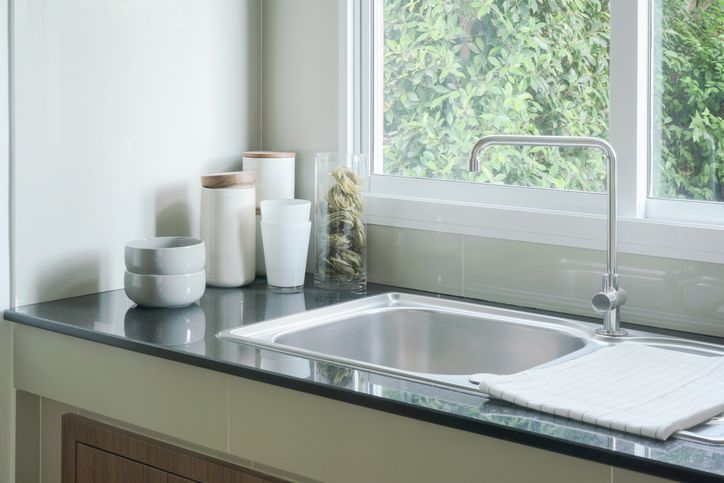A kitchen sink is sitting on a counter next to a window.
