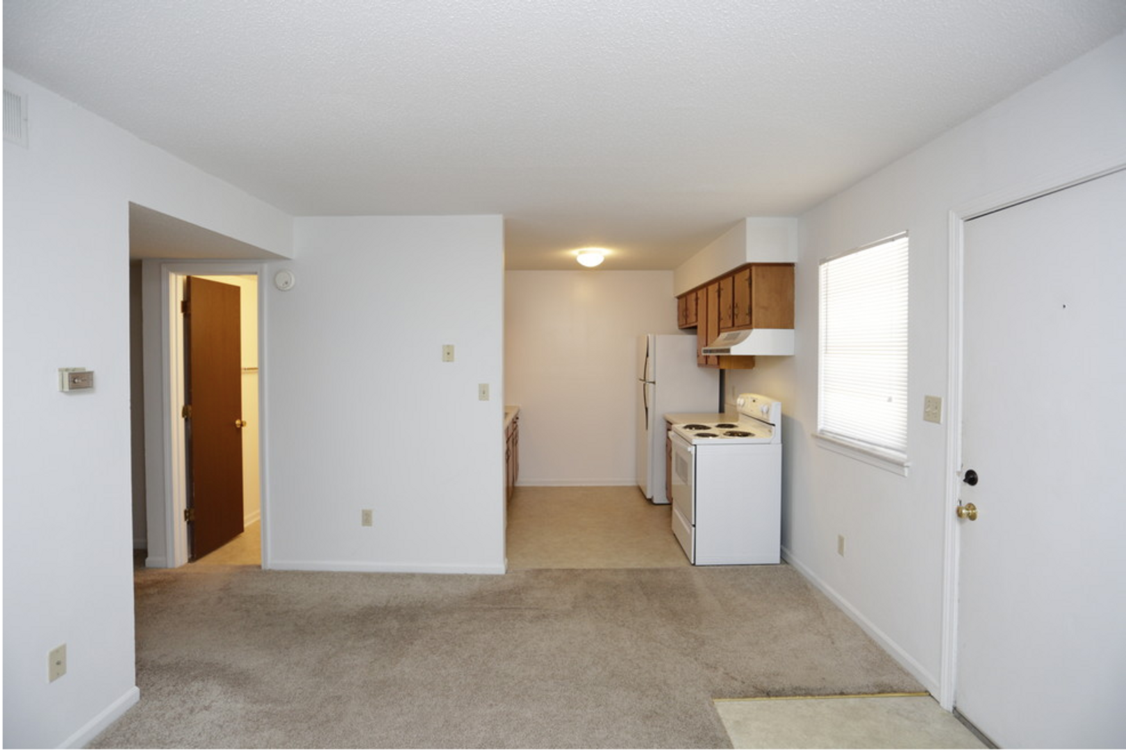 A living room with a stove and refrigerator in it