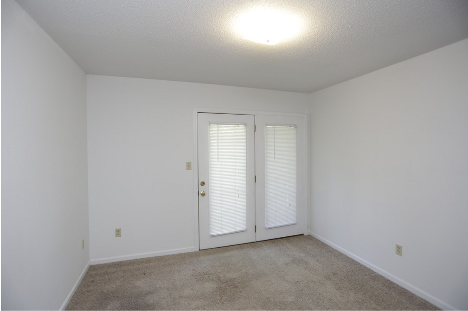 An empty room with white walls and a sliding glass door
