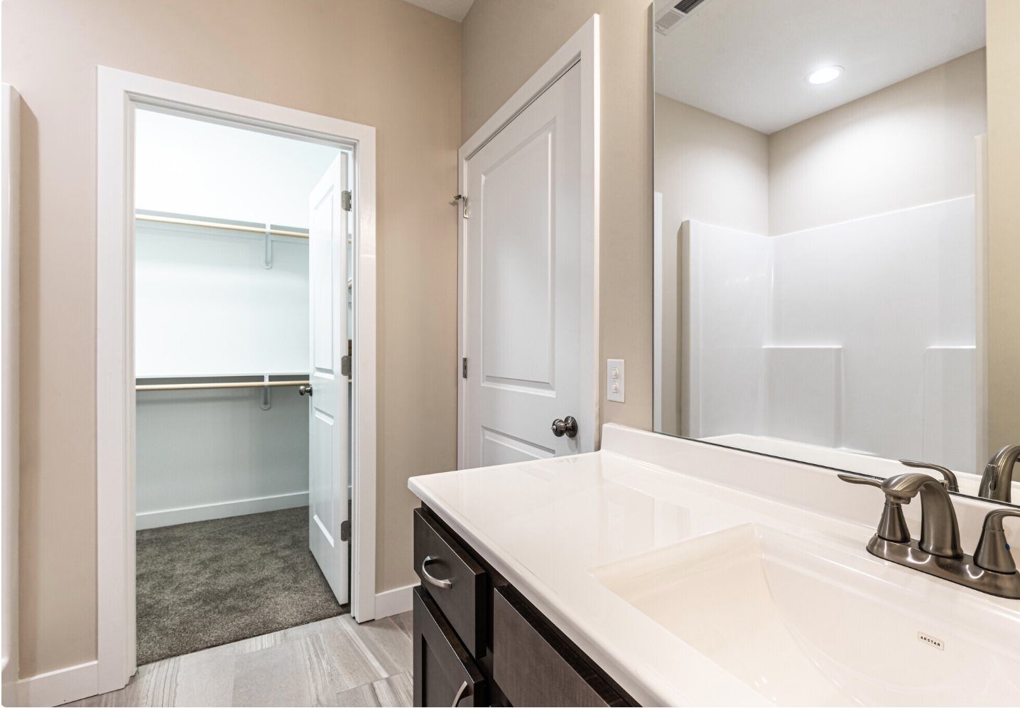A bathroom with a sink , mirror and walk in closet.