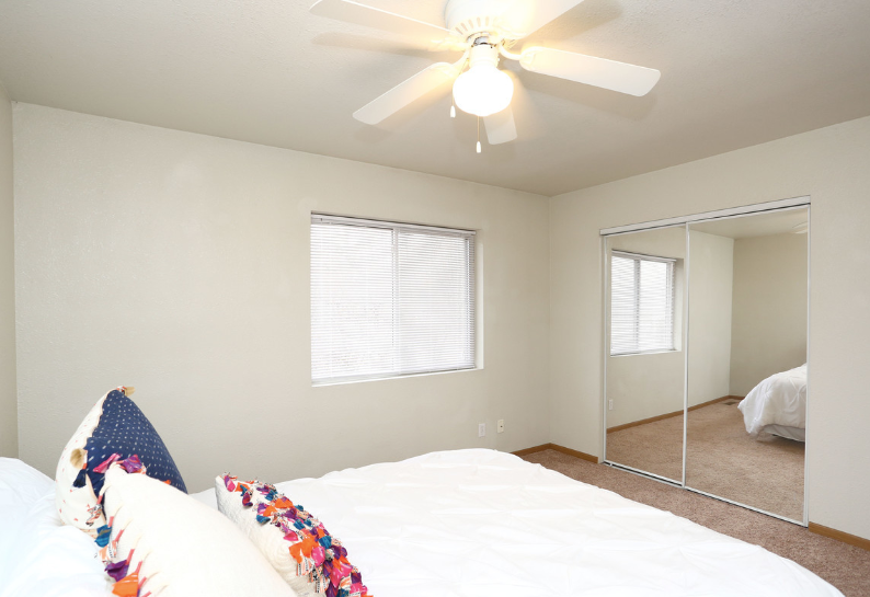 A bedroom with a bed and a ceiling fan