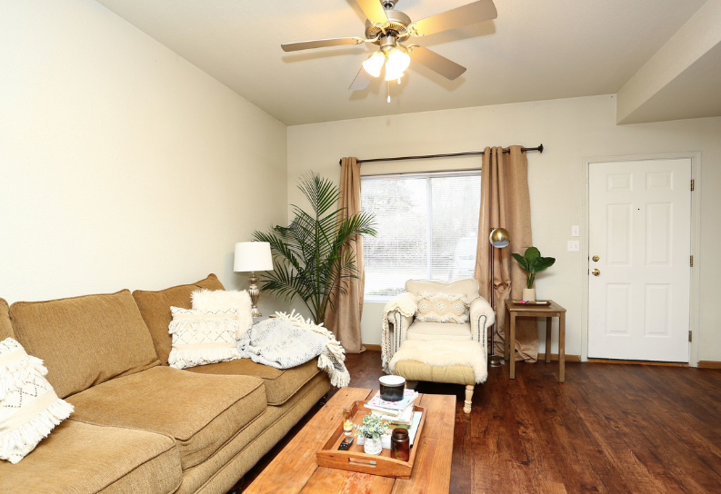 A living room with a couch a chair and a ceiling fan