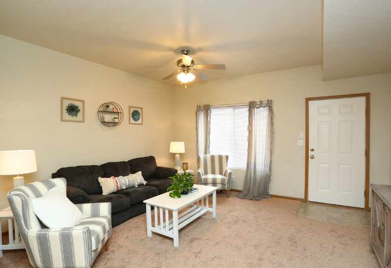 A living room with a couch and chairs and a ceiling fan