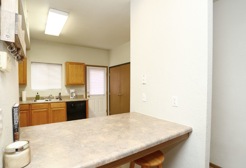 A kitchen with a counter and stools and a window
