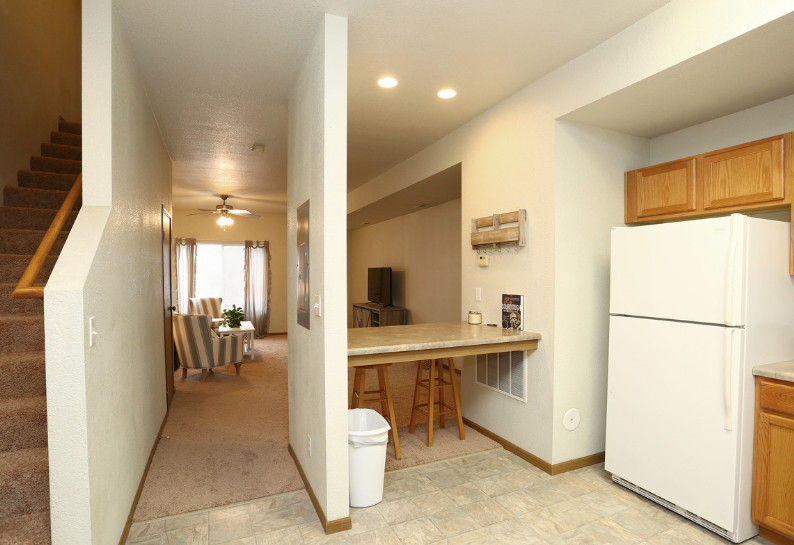 A kitchen with a white refrigerator and a trash can