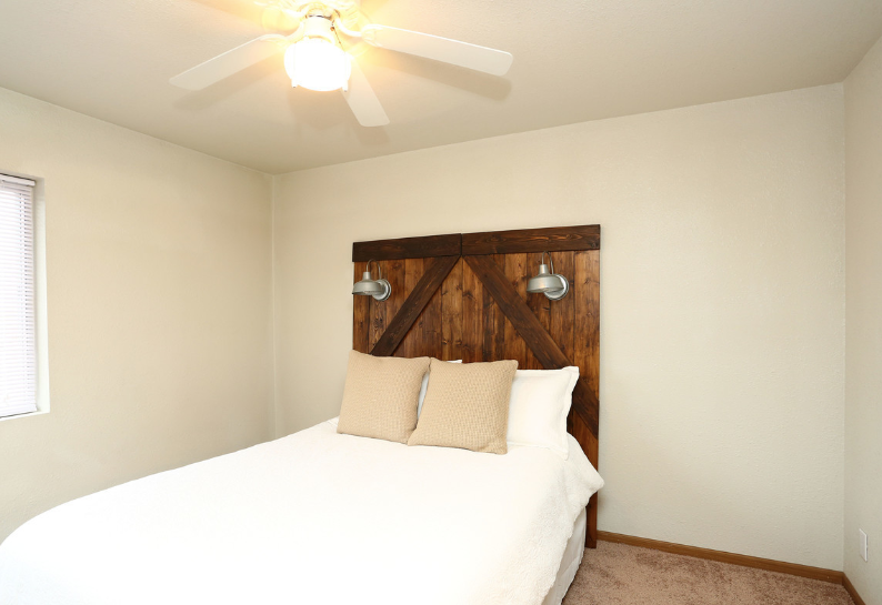 A bedroom with a bed and a ceiling fan
