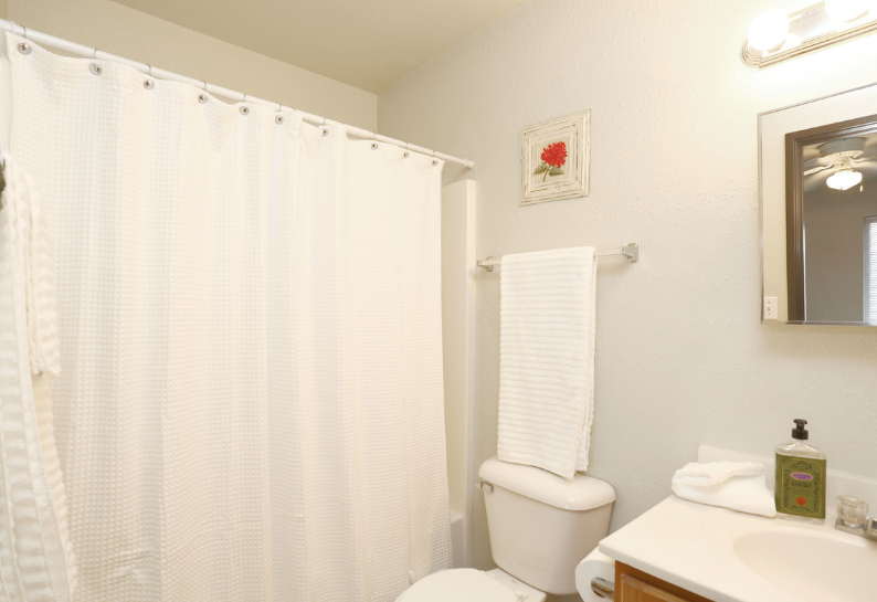 A bathroom with a toilet , sink , shower curtain and mirror.