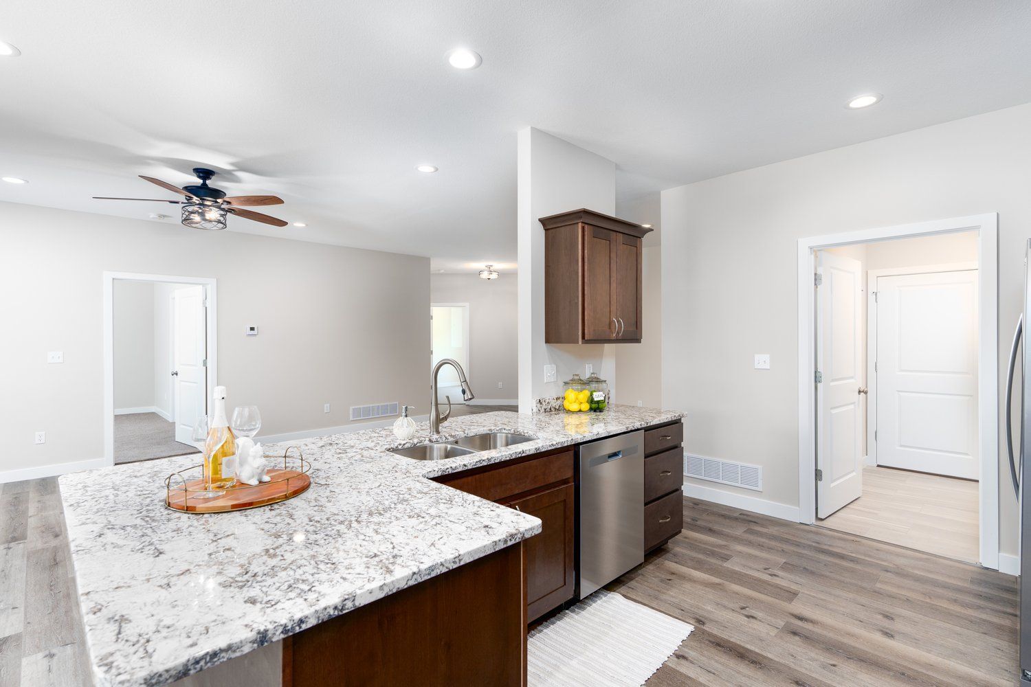 A kitchen with granite counter tops , stainless steel appliances , and a ceiling fan.