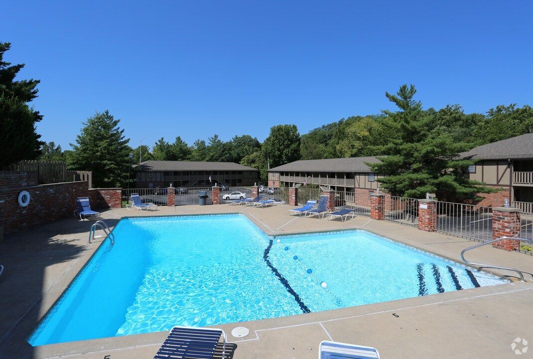 A large swimming pool is surrounded by chairs and buildings.