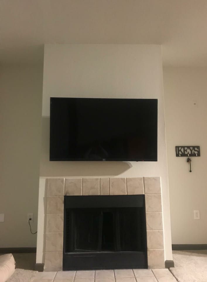 A flat screen tv mounted above a fireplace in a living room