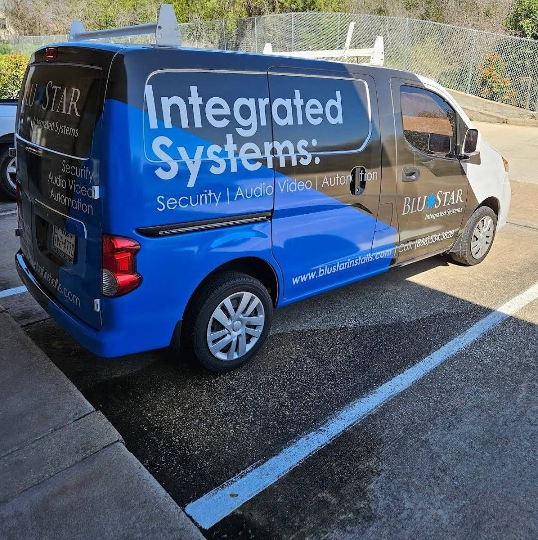 A blue van with integrated systems written on the side is parked in a parking lot.