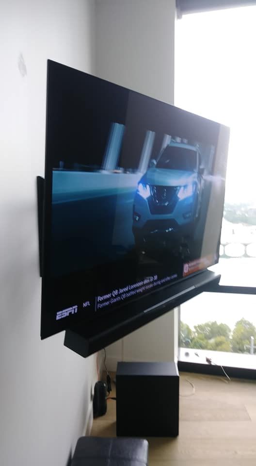 A flat screen tv is mounted on a wall next to a window.