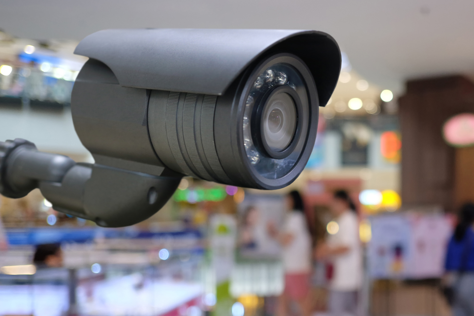 A security camera is hanging from the ceiling in a shopping mall.