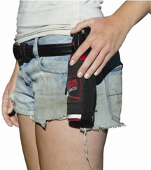 Woman holding a black holster on her thigh, likely containing pepper spray. She is wearing denim shorts and a white shirt.