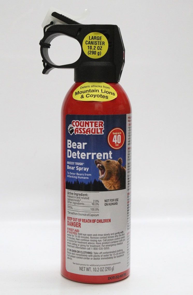 Man points a gun at a brown bear in a forest setting. Yellow signs mark 15 ft and 30 ft distances.