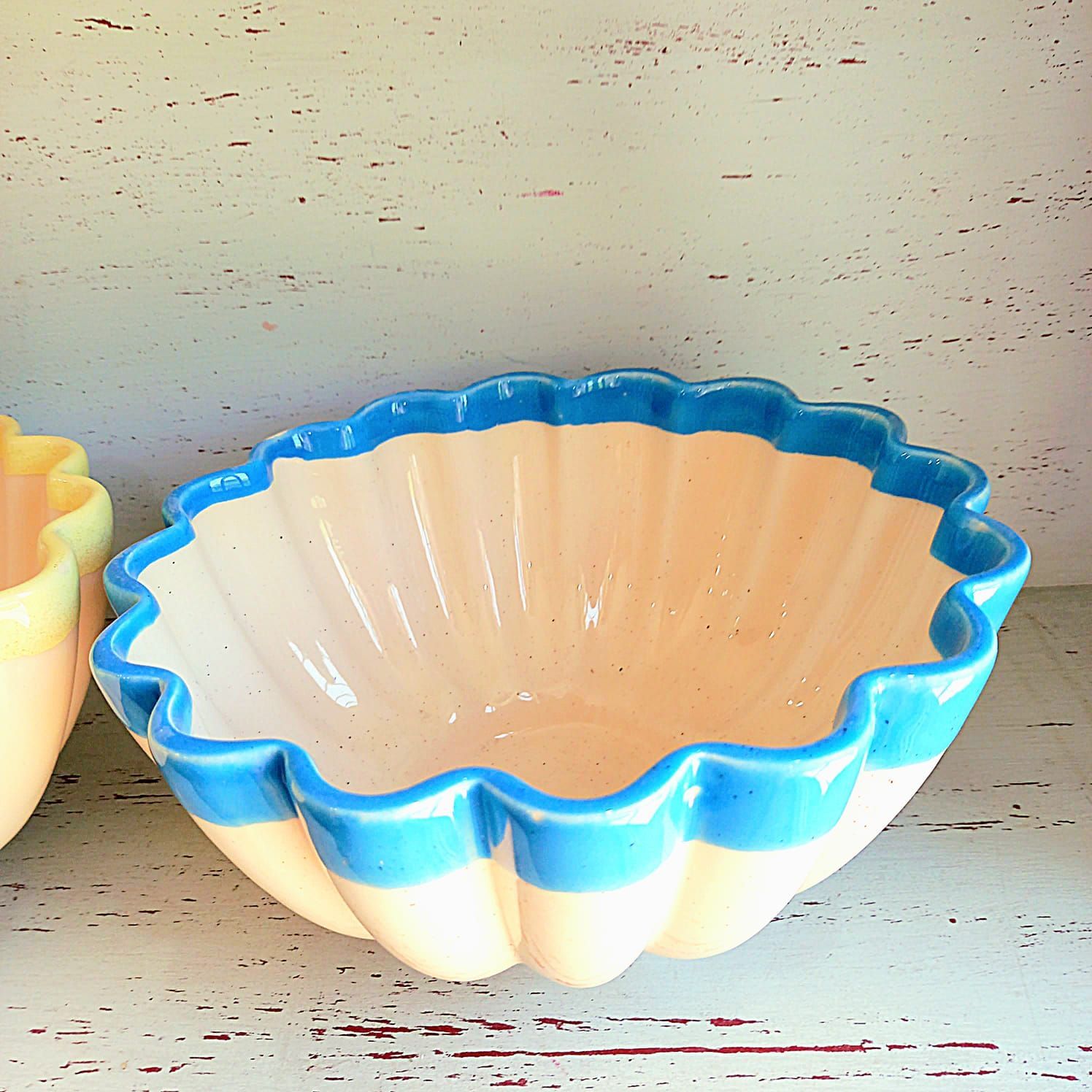 Dos cuencos amarillos y azules están sobre un estante.