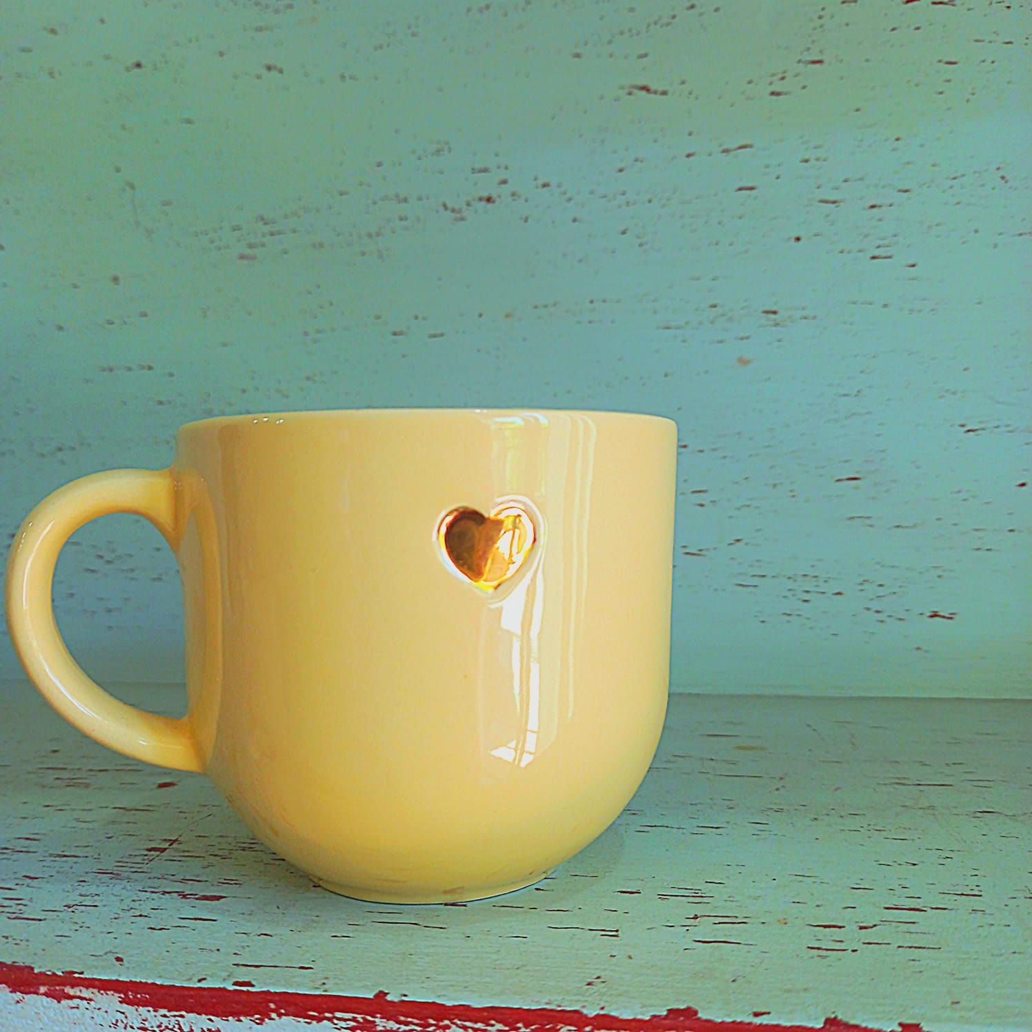 Una taza blanca con un corazón amarillo encima.