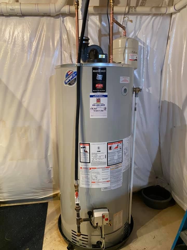 A water heater is sitting in a room next to a ladder.
