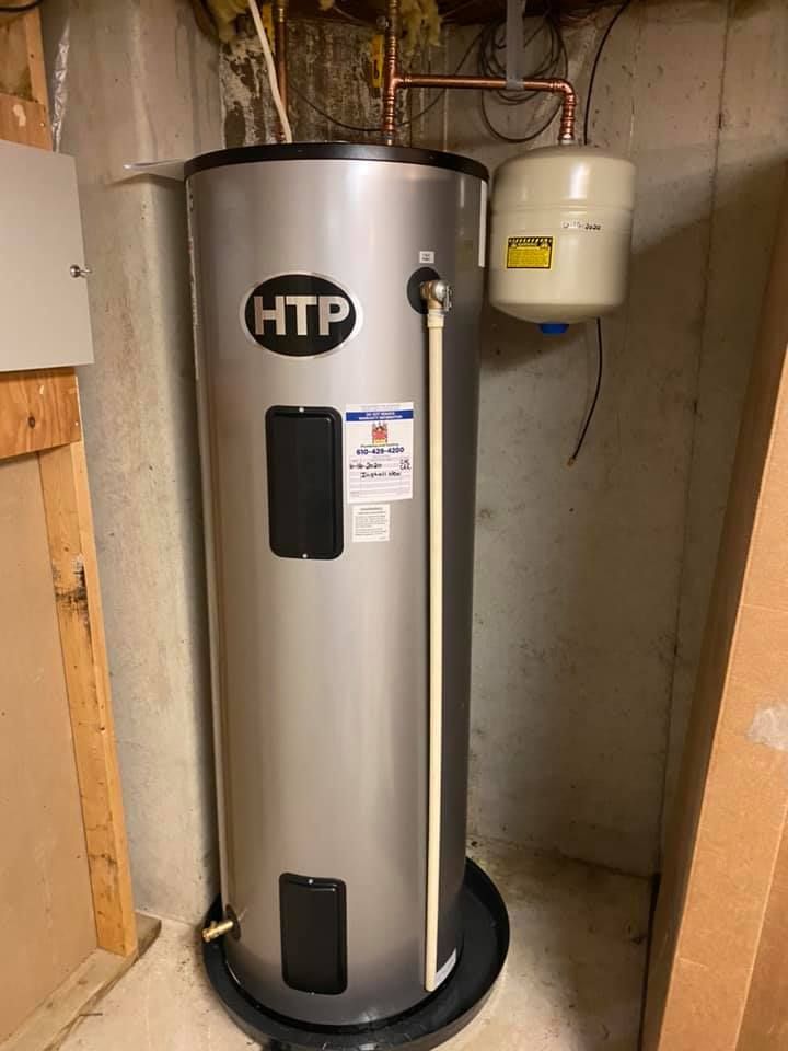 A stainless steel water heater is sitting in a basement next to a wall.
