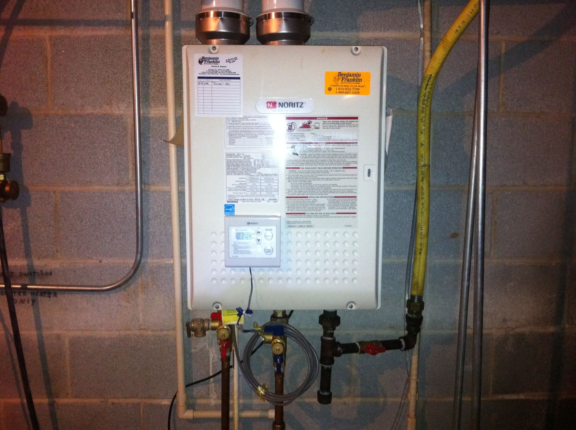 A water heater is mounted to a brick wall