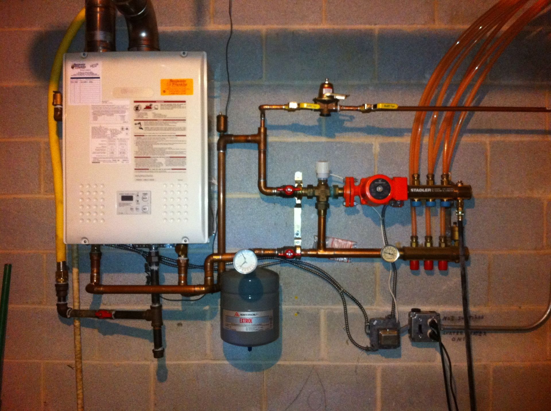 A boiler is mounted to a brick wall with copper pipes