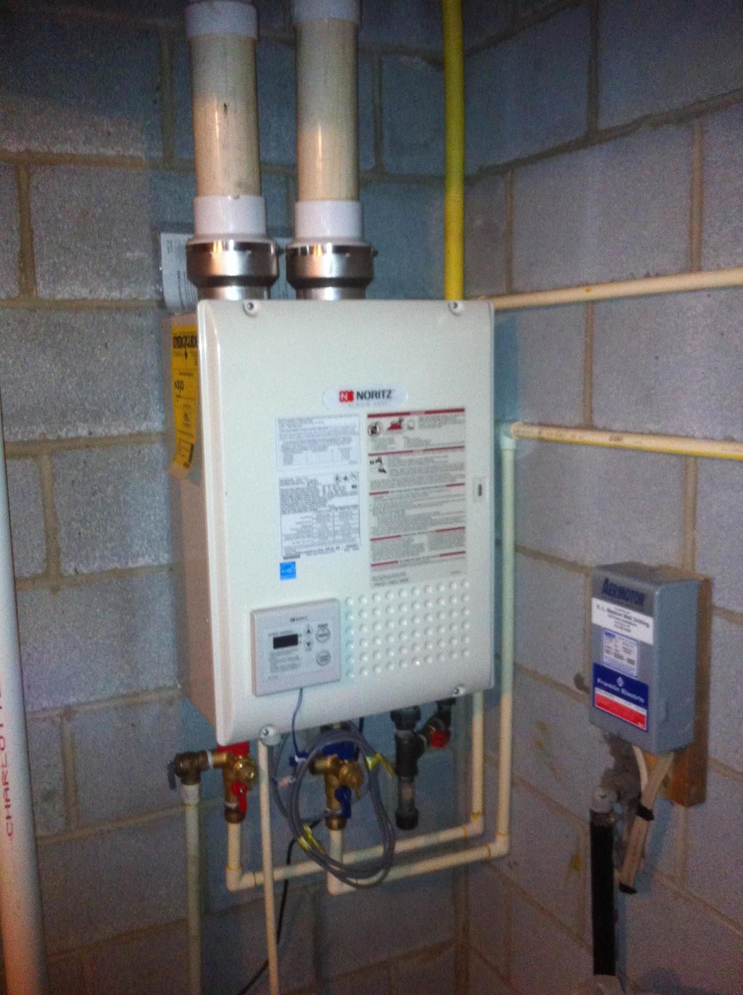 A water heater is mounted to a brick wall