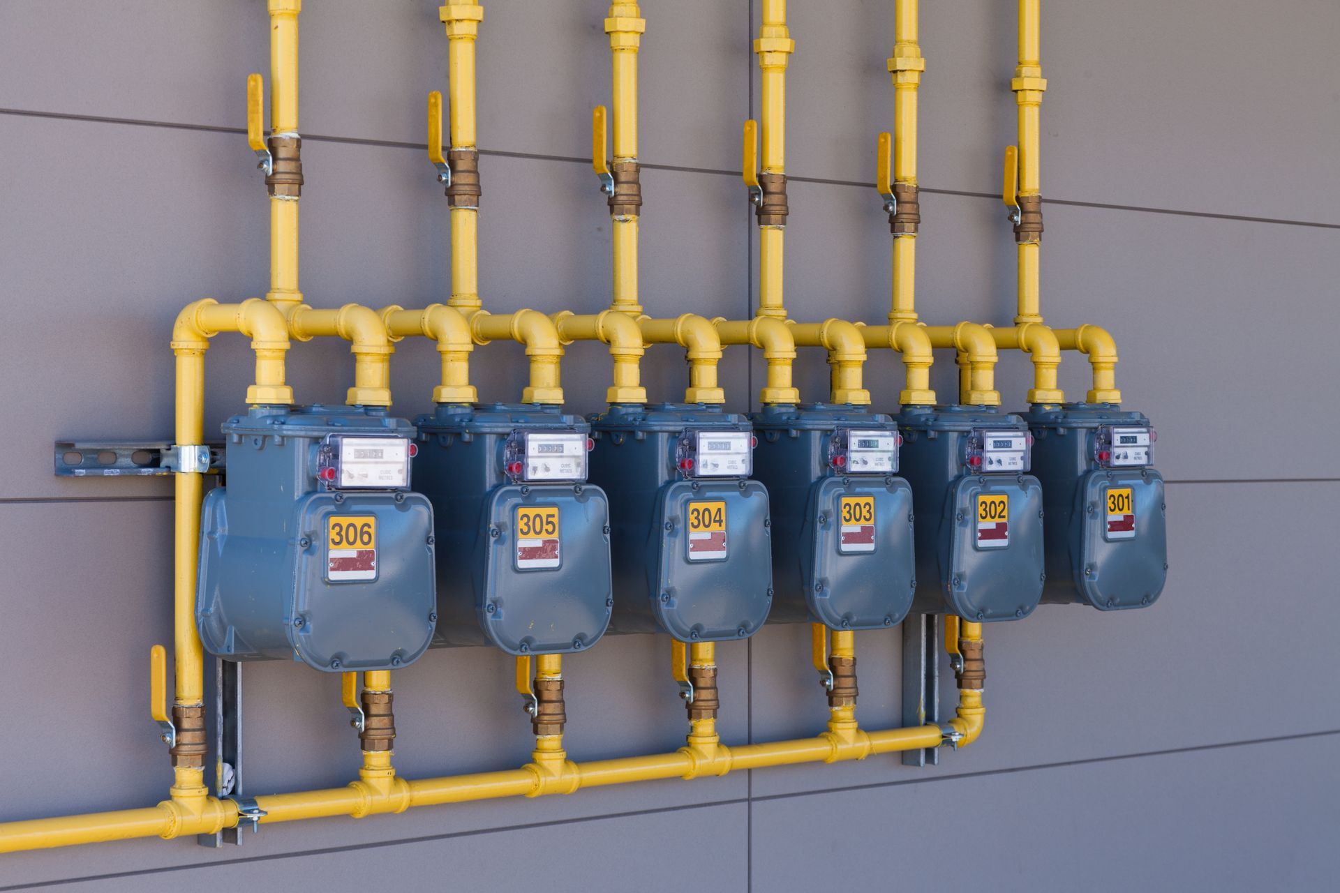 A row of gas meters are lined up on a wall.