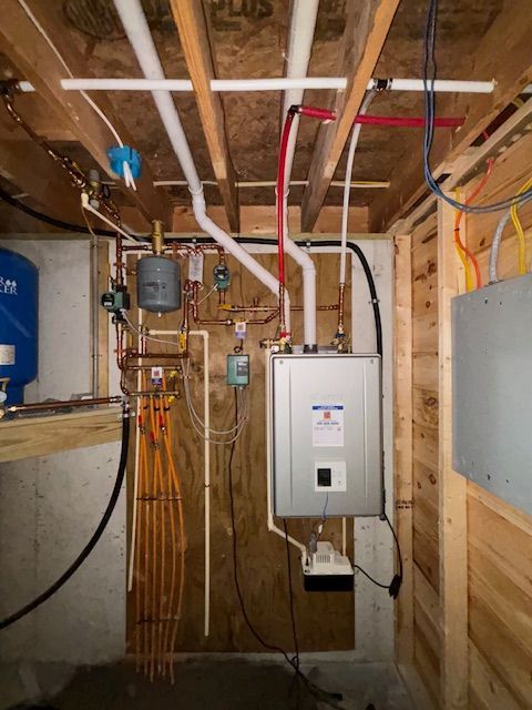 A room with a water heater and pipes hanging from the ceiling