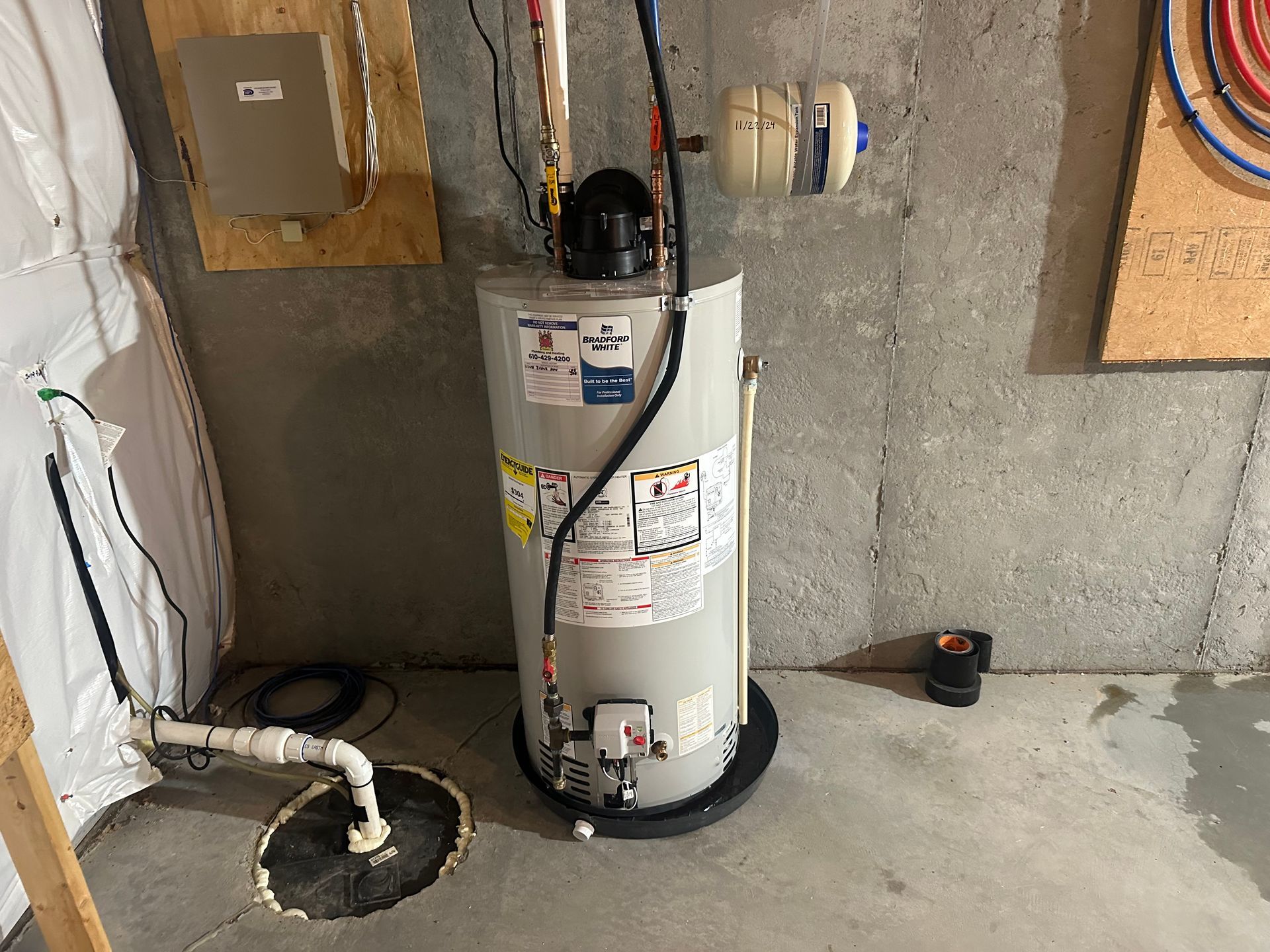 A water heater is sitting in a basement next to a wall.