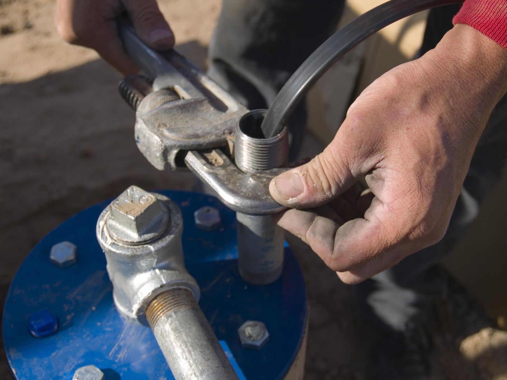 A person is working on a pipe with a wrench