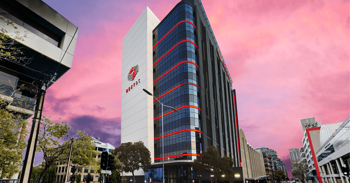 A large building with red stripes on the side of it is in the middle of a city.