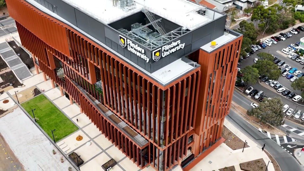 An aerial view of a large brick building with a parking lot in front of it.