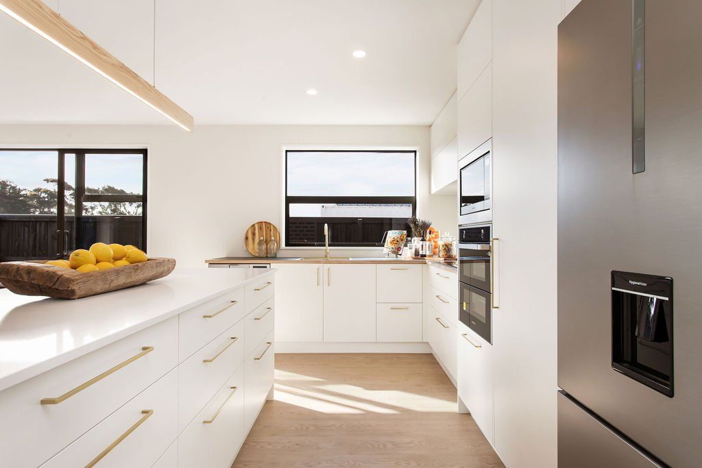 A kitchen with white cabinets and a stainless steel refrigerator.