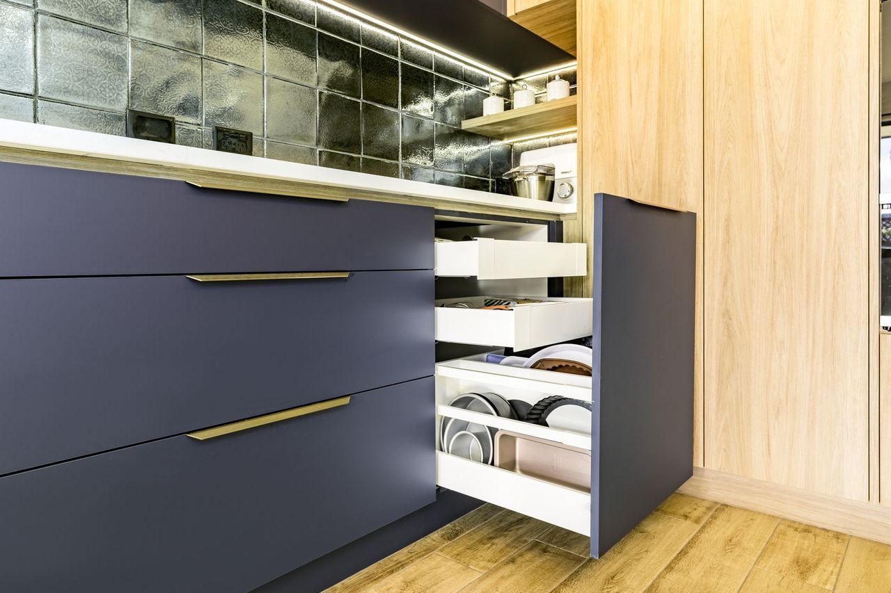 a kitchen with blue cabinets and wooden floors and drawers open .