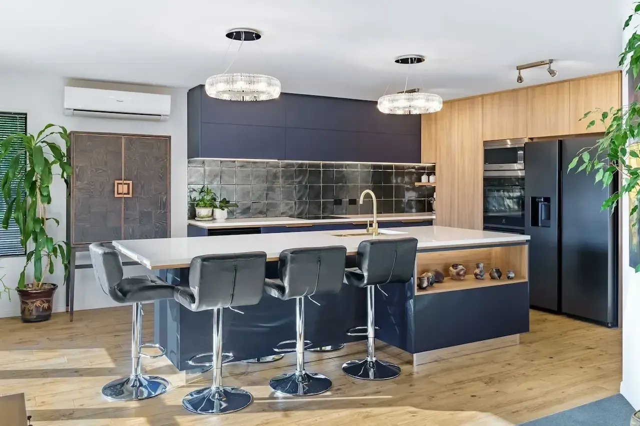 A kitchen with a large island , stools and a refrigerator.
