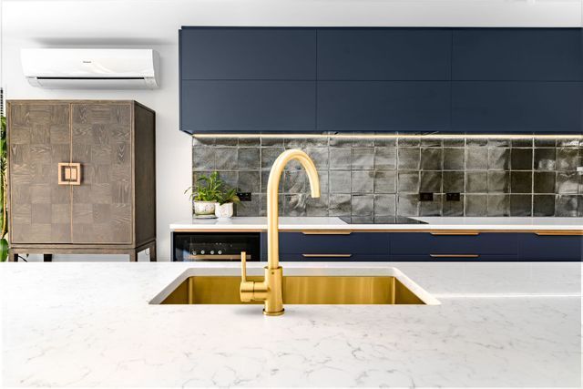 a kitchen with blue cabinets and a gold sink .