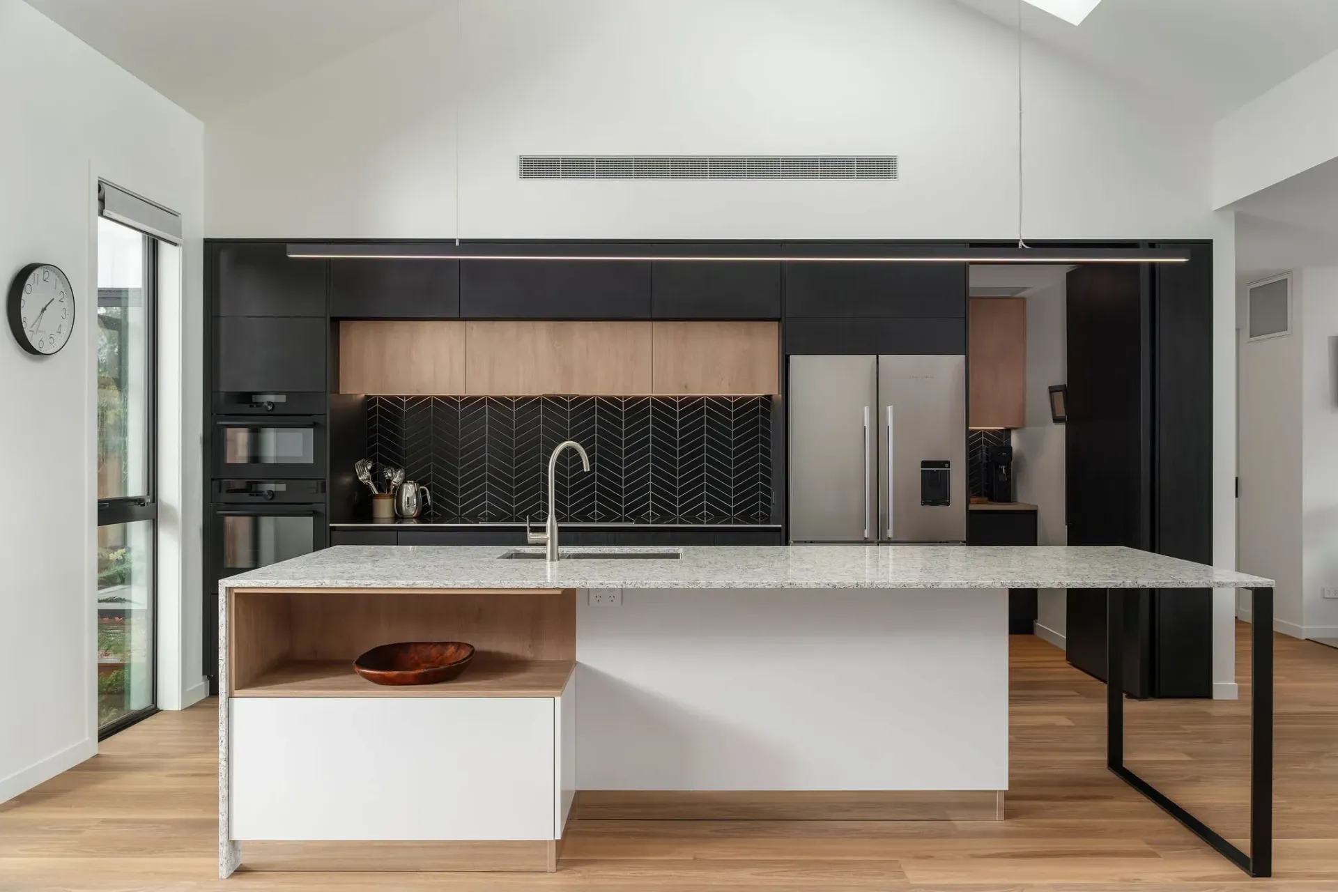 A kitchen with black and white cabinets, a stainless steel refrigerator