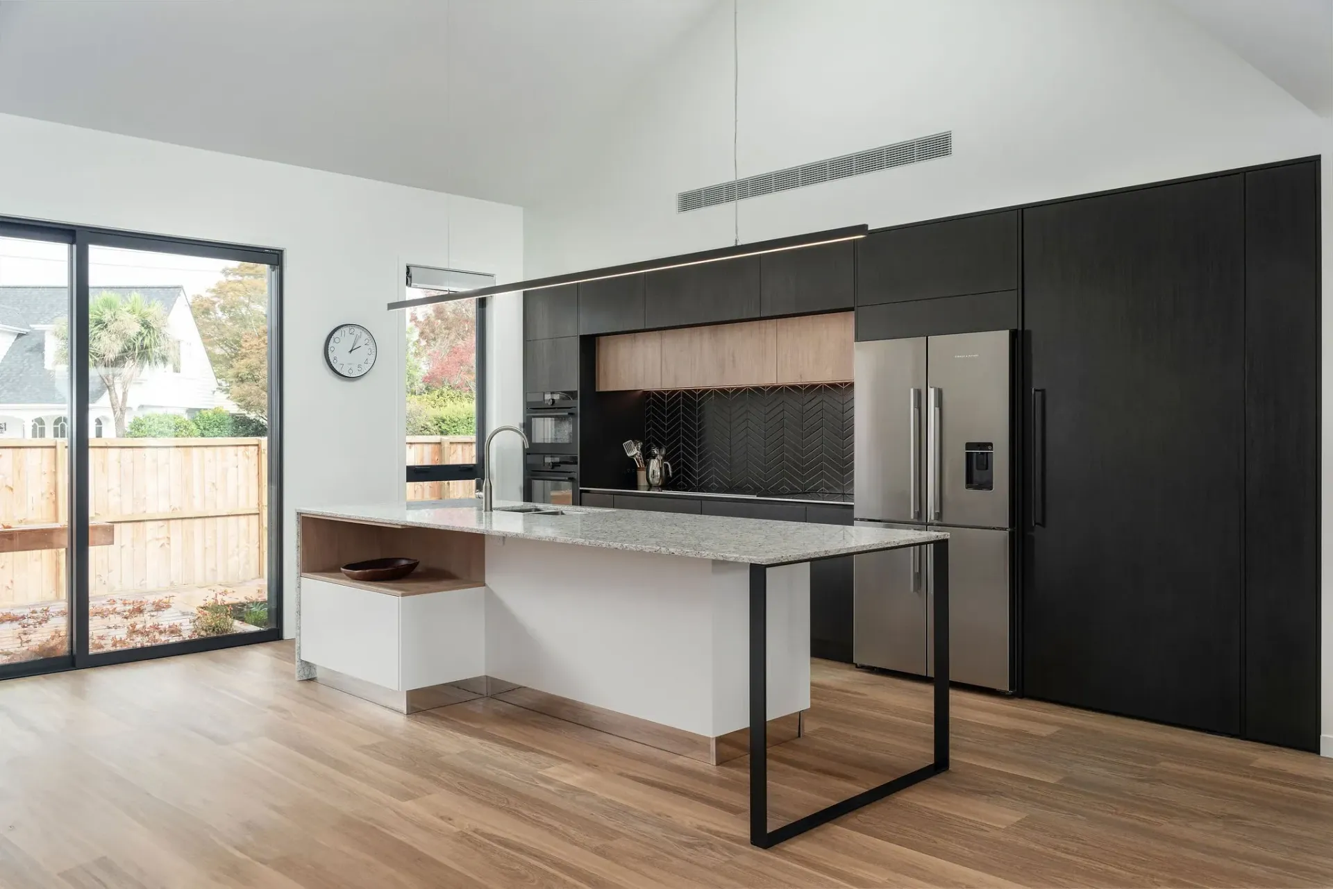 A kitchen with black cabinets and a large island in the middle of the room.