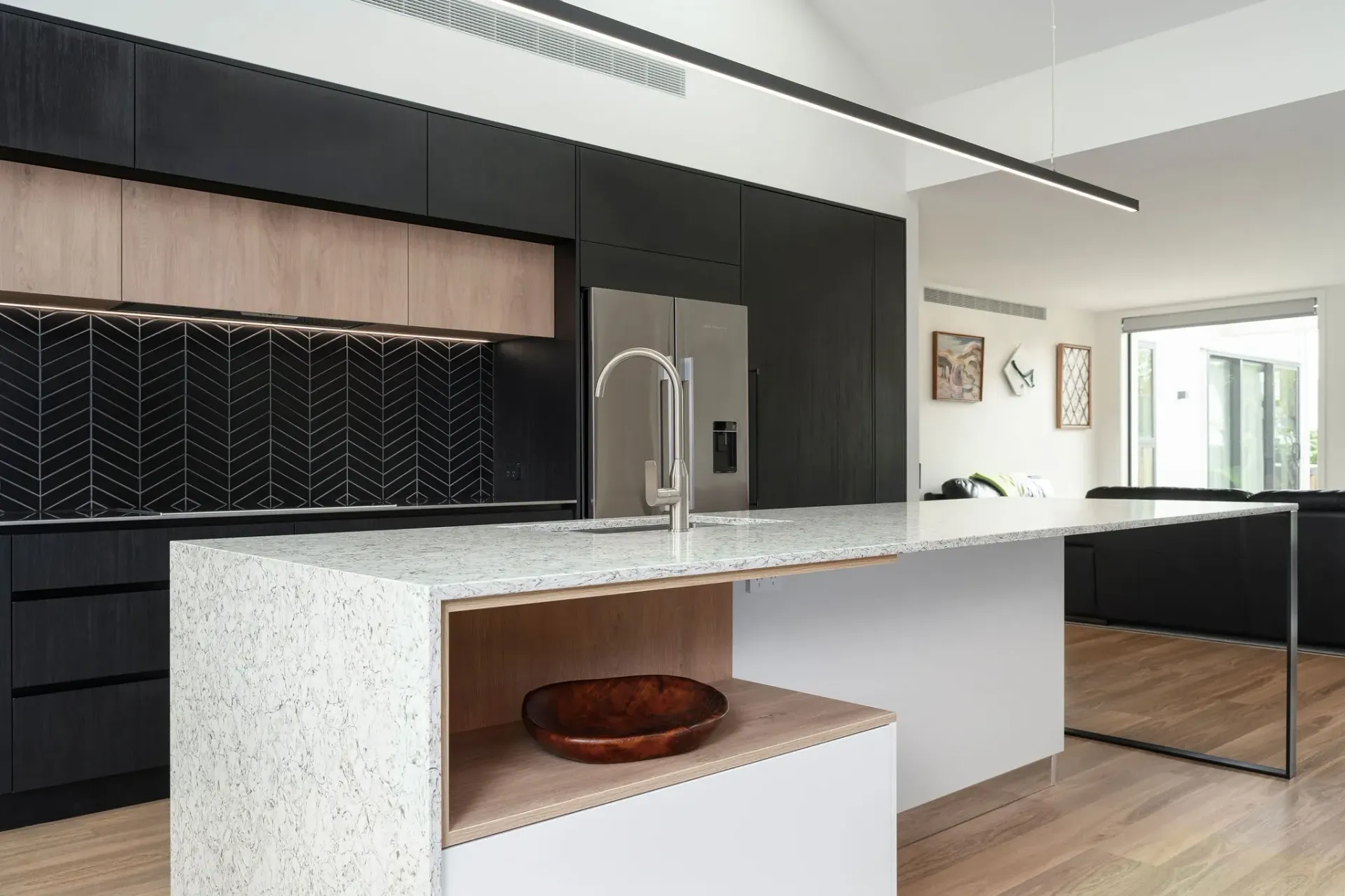 A kitchen with black cabinets , white counter tops , and a large island.