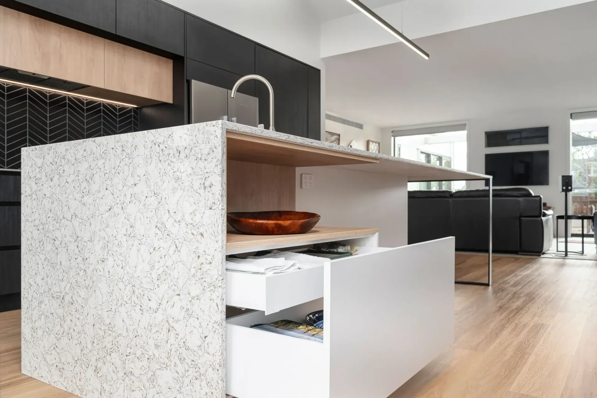 A kitchen with a large island and drawers open.