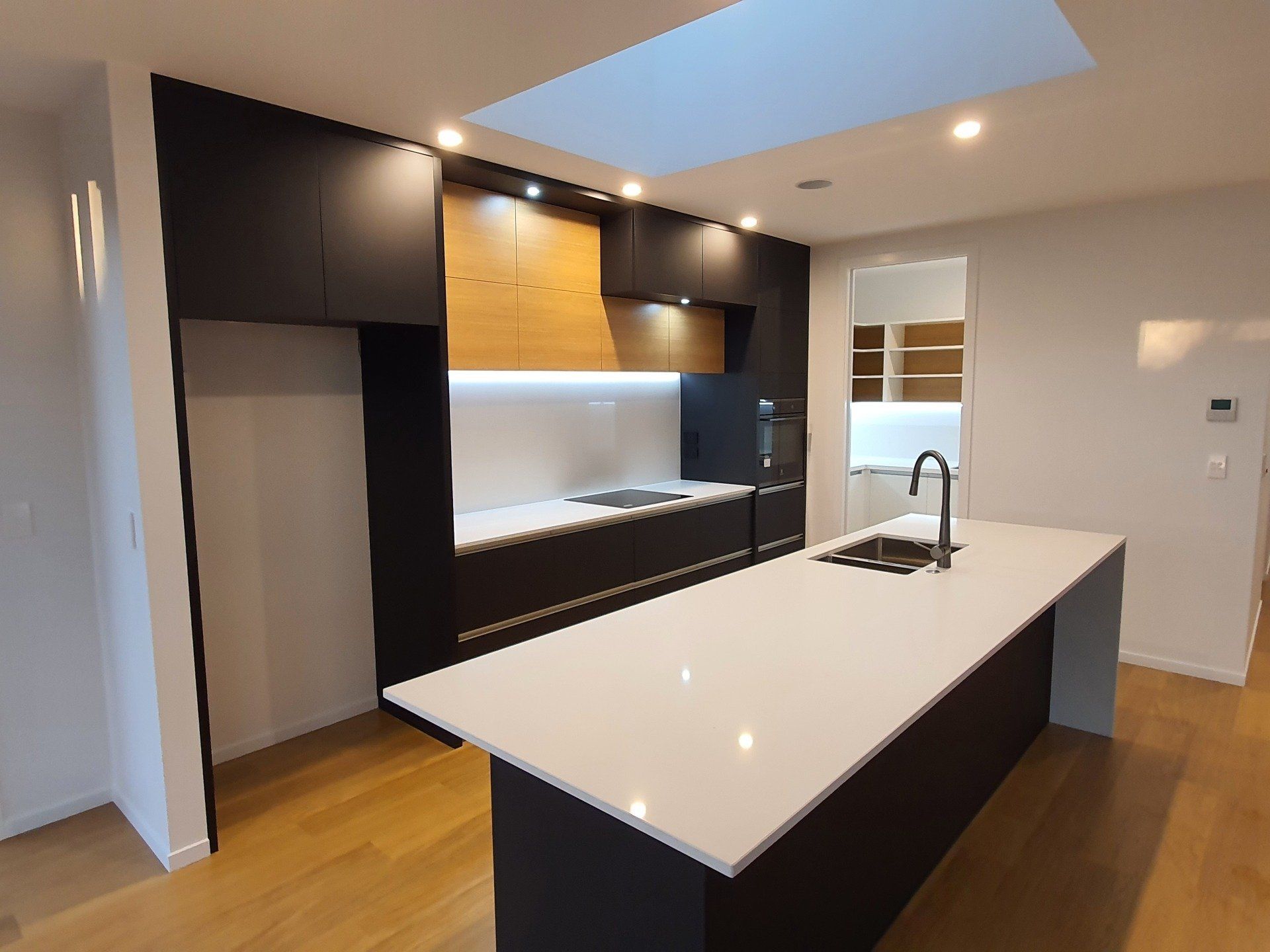 A kitchen with black cabinets and white counter tops and a large island.