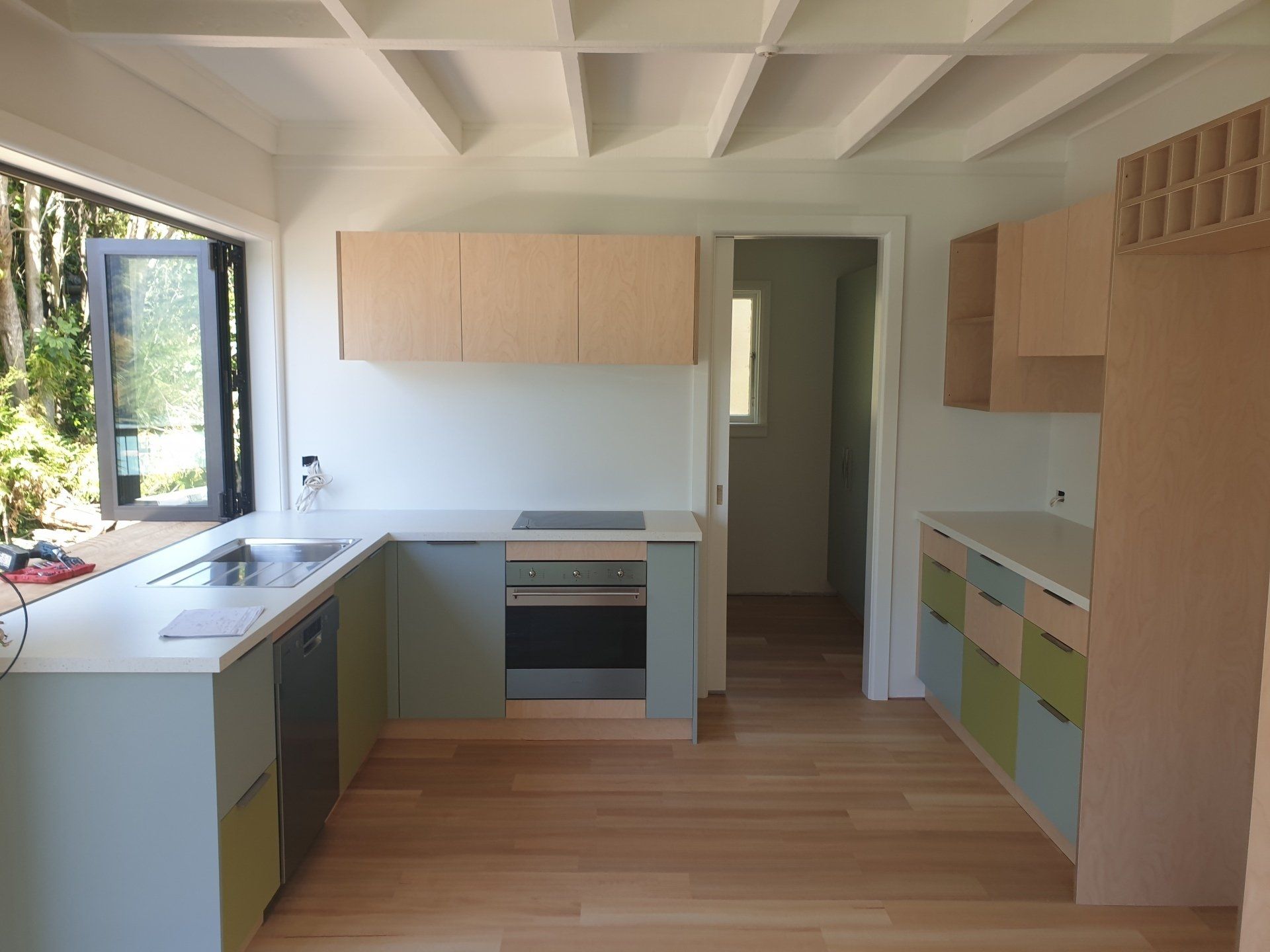 A kitchen with wooden cabinets , a stove , a sink , and a window.