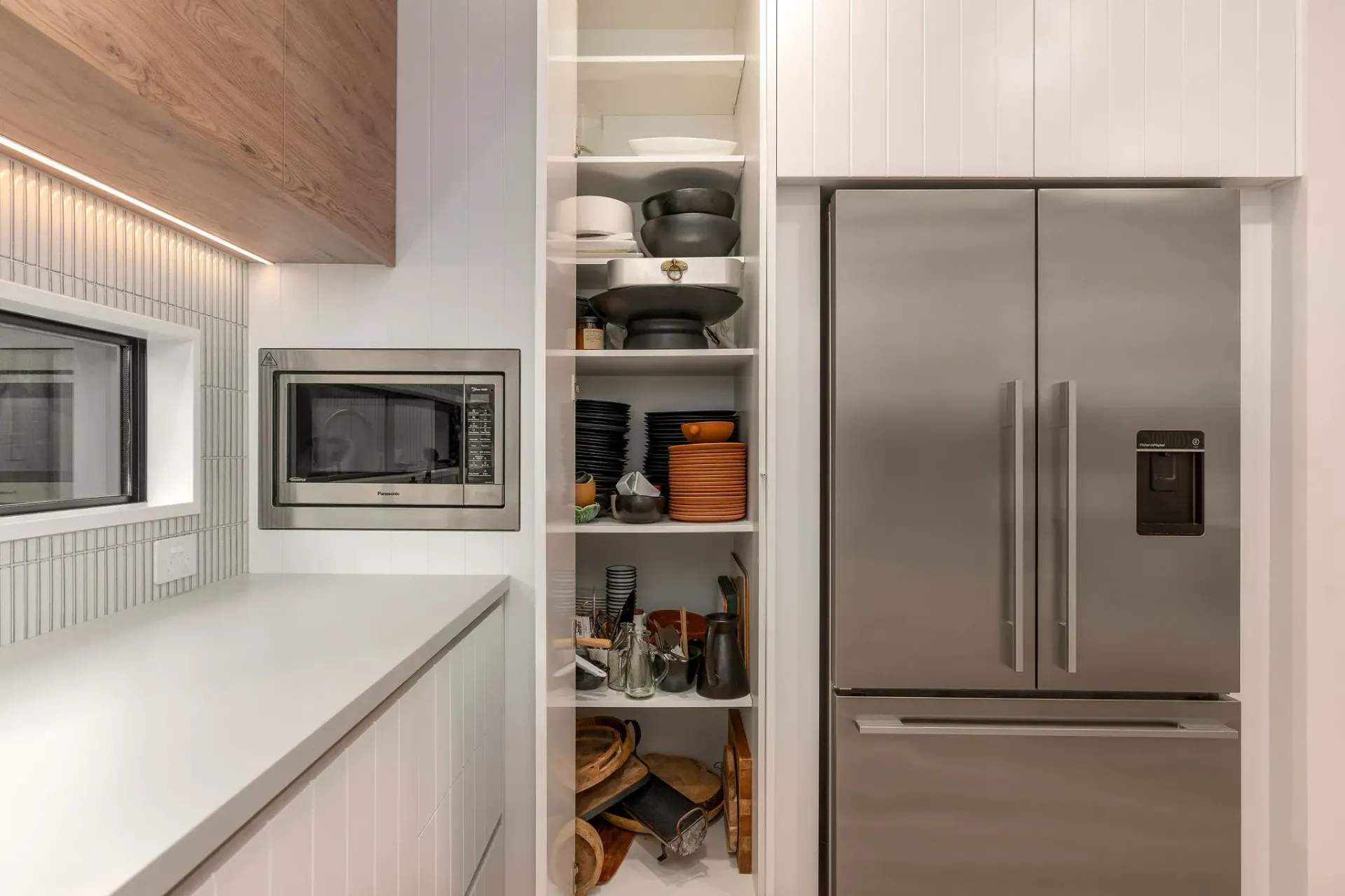 A kitchen with a stainless steel refrigerator and a pantry.