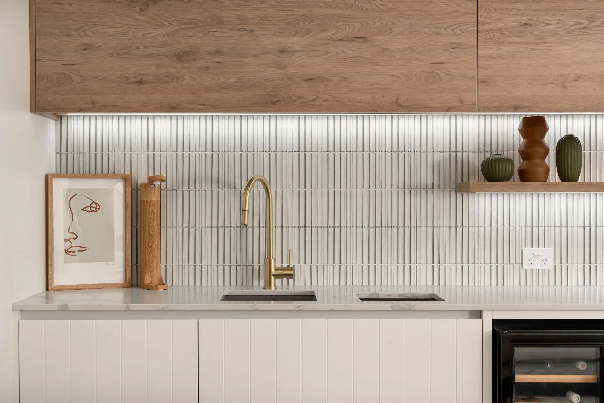 A kitchen with white cabinets , a sink , and a wine cooler.