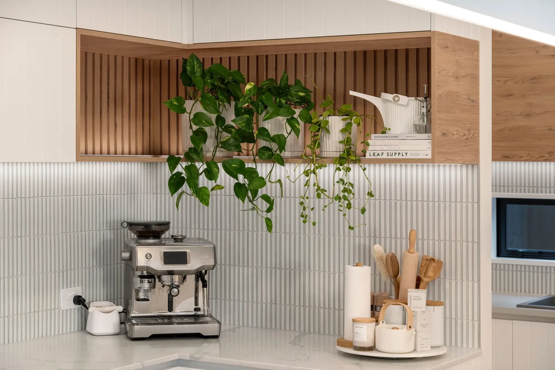 A kitchen with a coffee maker , pots and pans , and a plant hanging from the ceiling.
