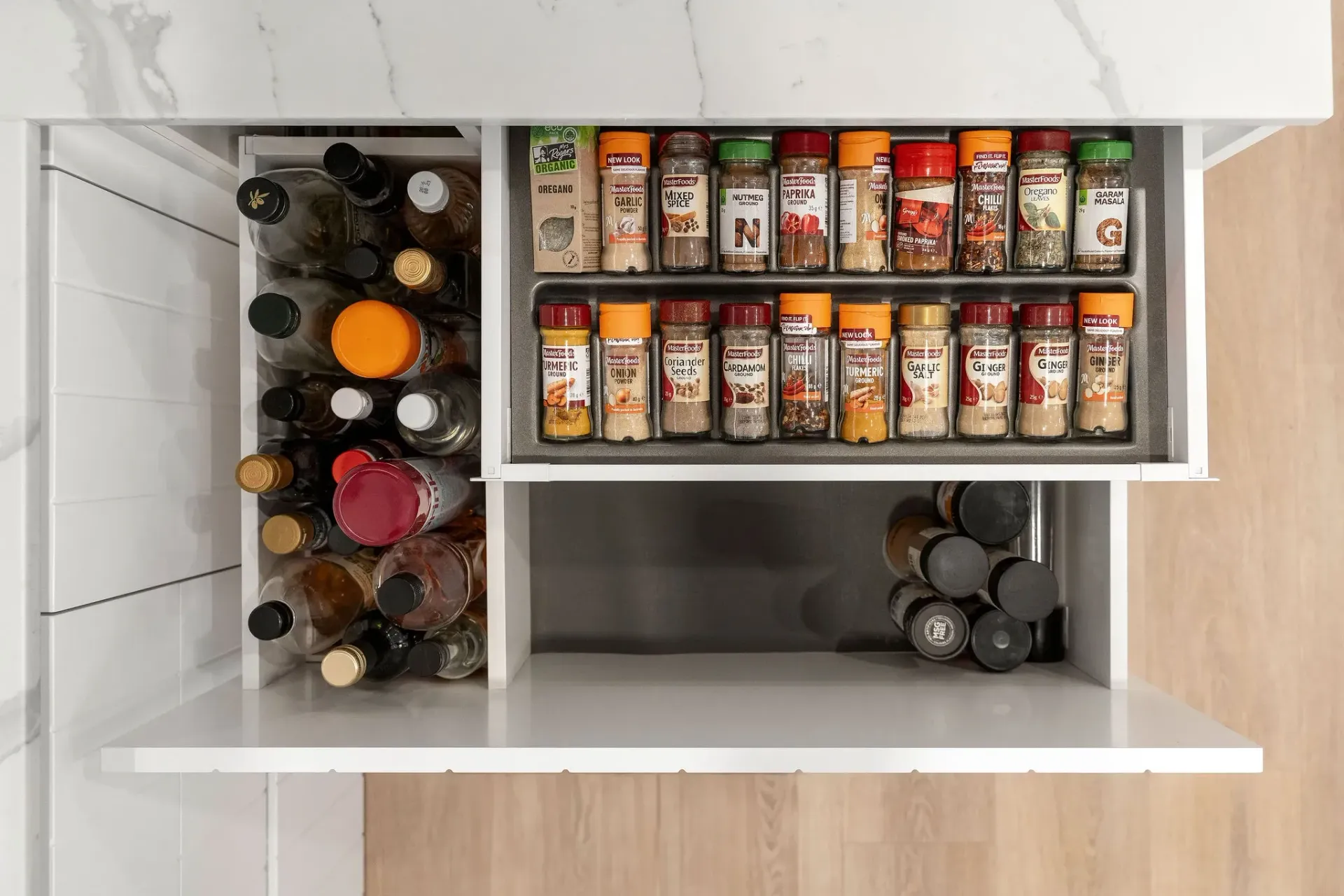A kitchen drawer filled with bottles and jars of spices.