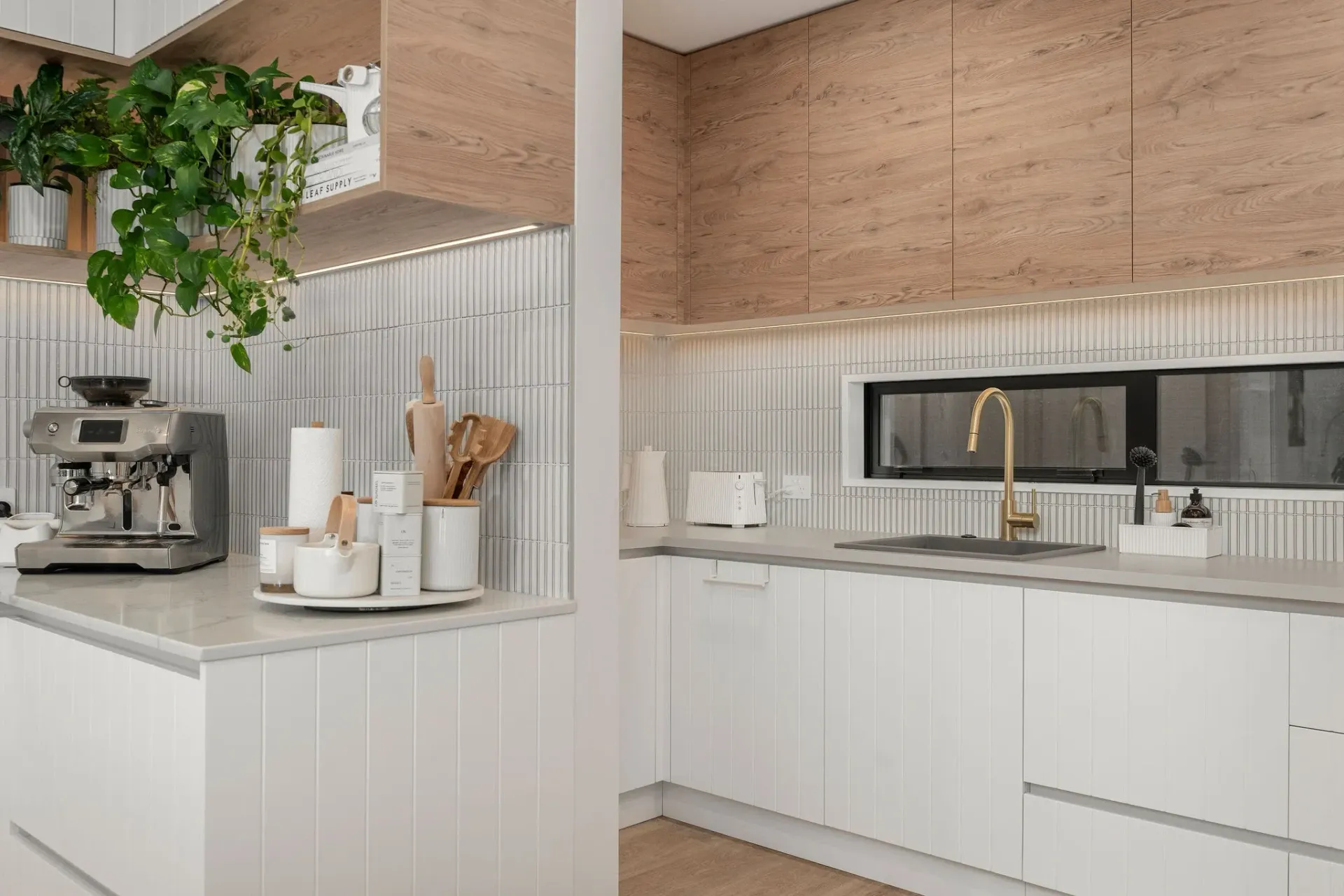 A kitchen with white cabinets , a sink , and a coffee maker.