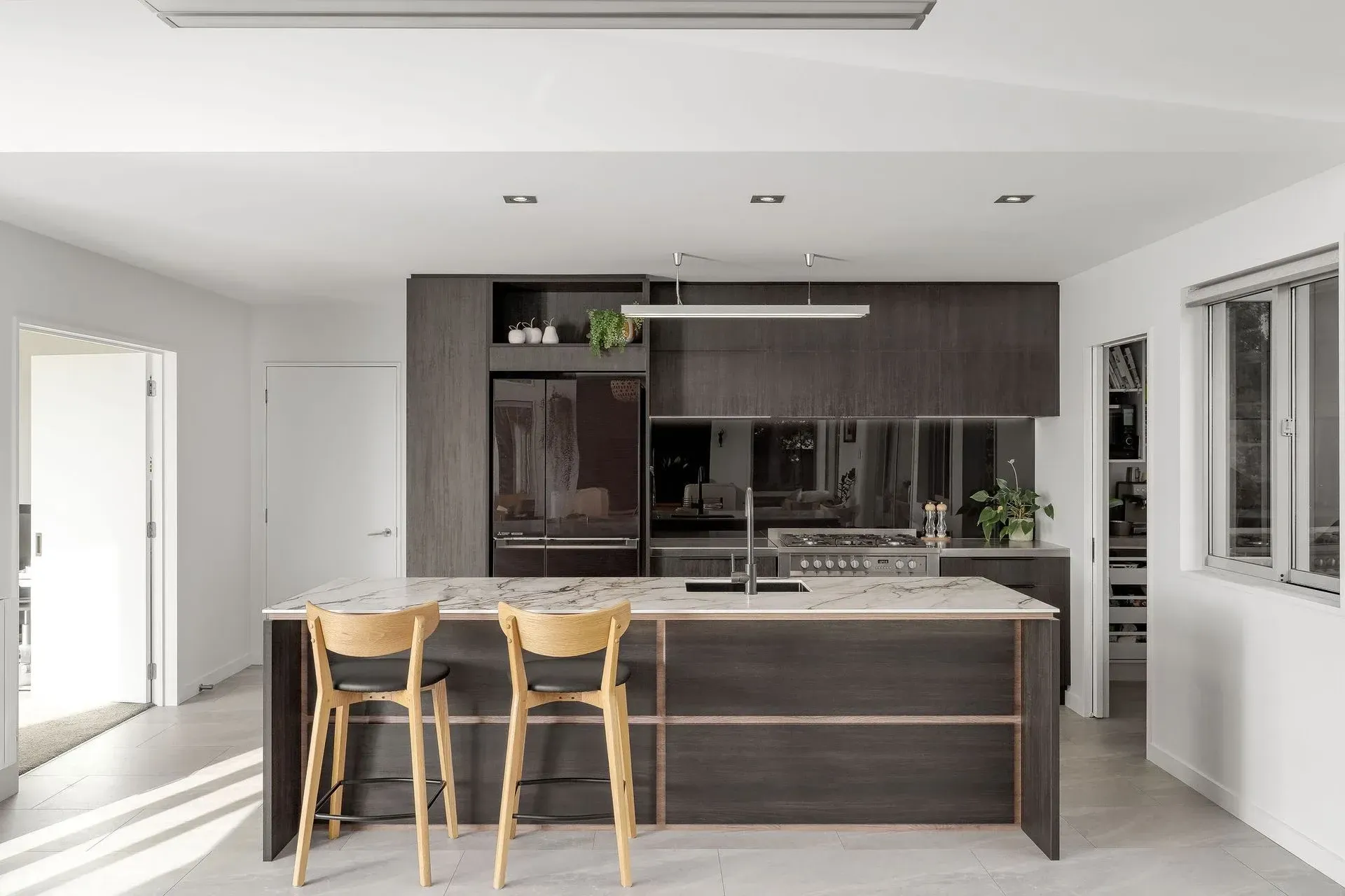 A kitchen with a large island , stools and a refrigerator.