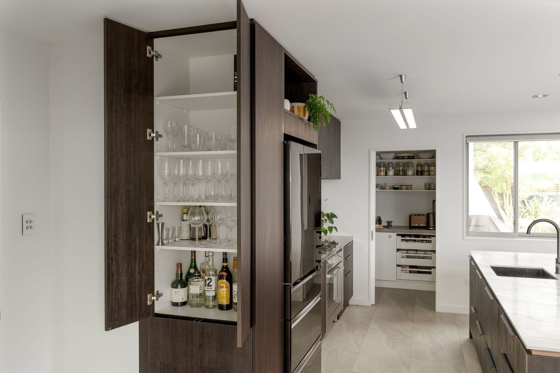 A kitchen with a pantry filled with bottles and glasses.