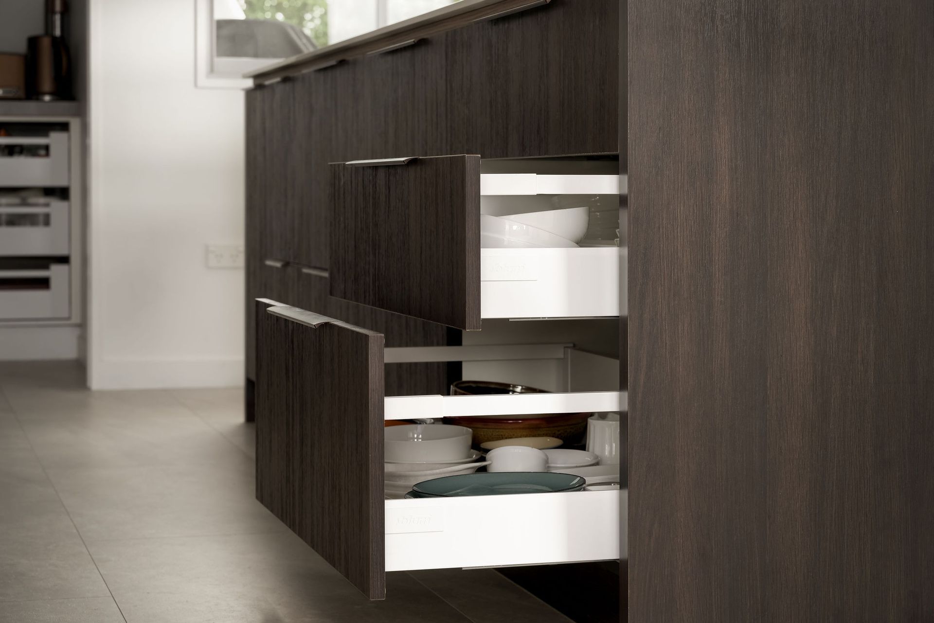 A kitchen with a lot of drawers filled with plates and bowls.